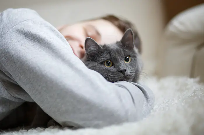 man huggng cat on bed 1